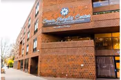 Exterior view of Crown Heights Center for Nursing and Rehabilitation, a multi-story brick building with large windows and the facility's name displayed prominently on the facade.