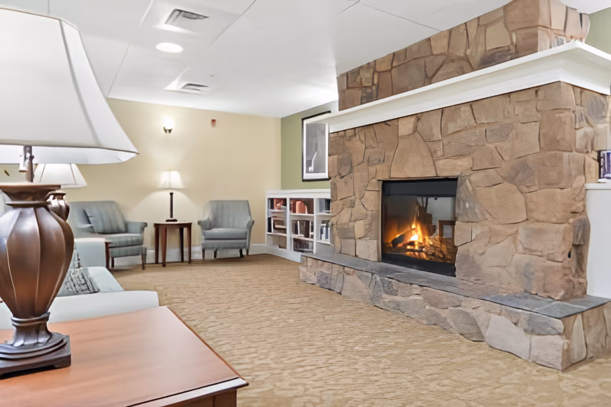 Cozy lounge with a stone fireplace, armchairs, side tables, and lamps.