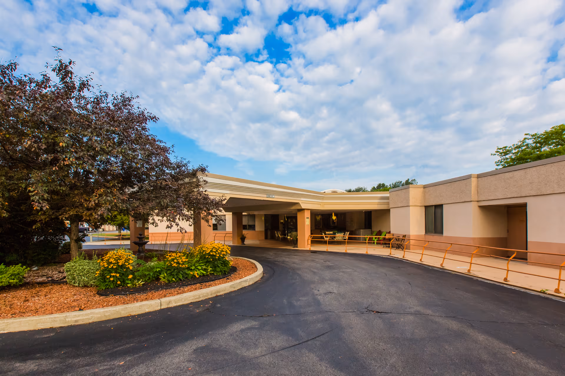 Front entrance of Northgate Health Care Facility with a covered drive-through, circular driveway, and landscaped flower beds.