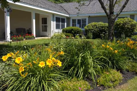 Taylor Community exterior with landscaped garden and bright yellow flowers in foreground