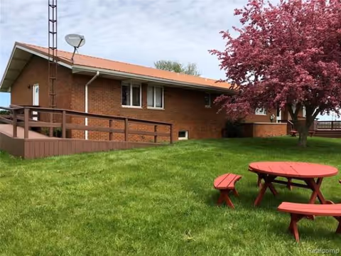 Meadow Breeze brick building with wooden ramp and a red picnic table on a green lawn.