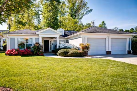 Front view of a single-story building with two garages, entrance, and landscaped lawn.