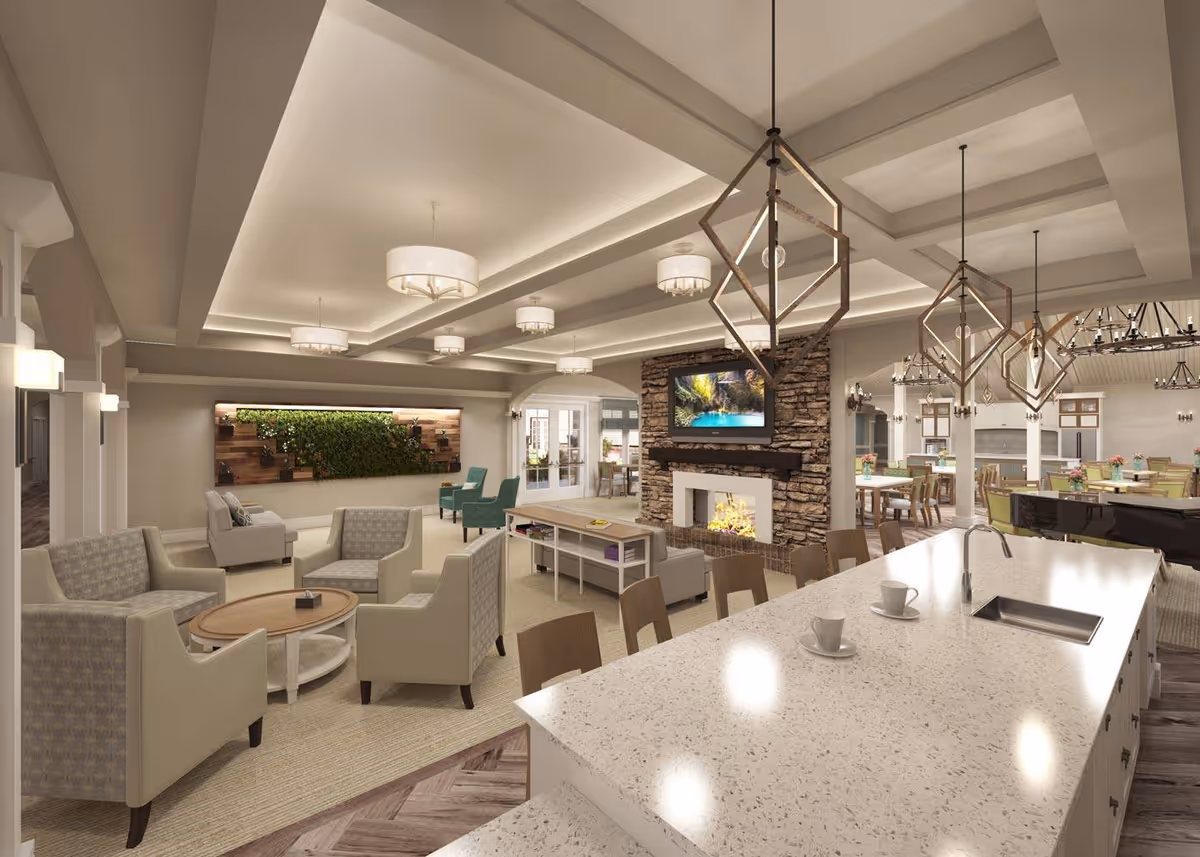 Spacious senior living common area with lounge seating around a fireplace, TV, dining tables, and a kitchen island with pendant lights.