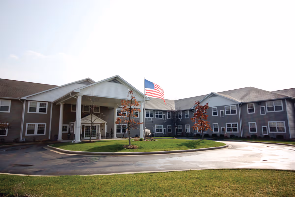 Front exterior view of Eagle Ridge of Decatur facility with a circular driveway, green lawn, several small trees, and an American flag flying on a flagpole in front of the entrance.