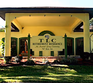 Front entrance of a retirement residence with a green sign and lawn.