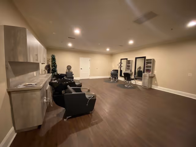 Spacious interior salon area with hair-washing stations, styling chairs, mirrors, and cabinetry on wood floors.