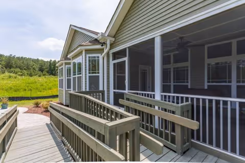Exterior view of Avendelle Assisted Living with a screened porch and wooden ramp.