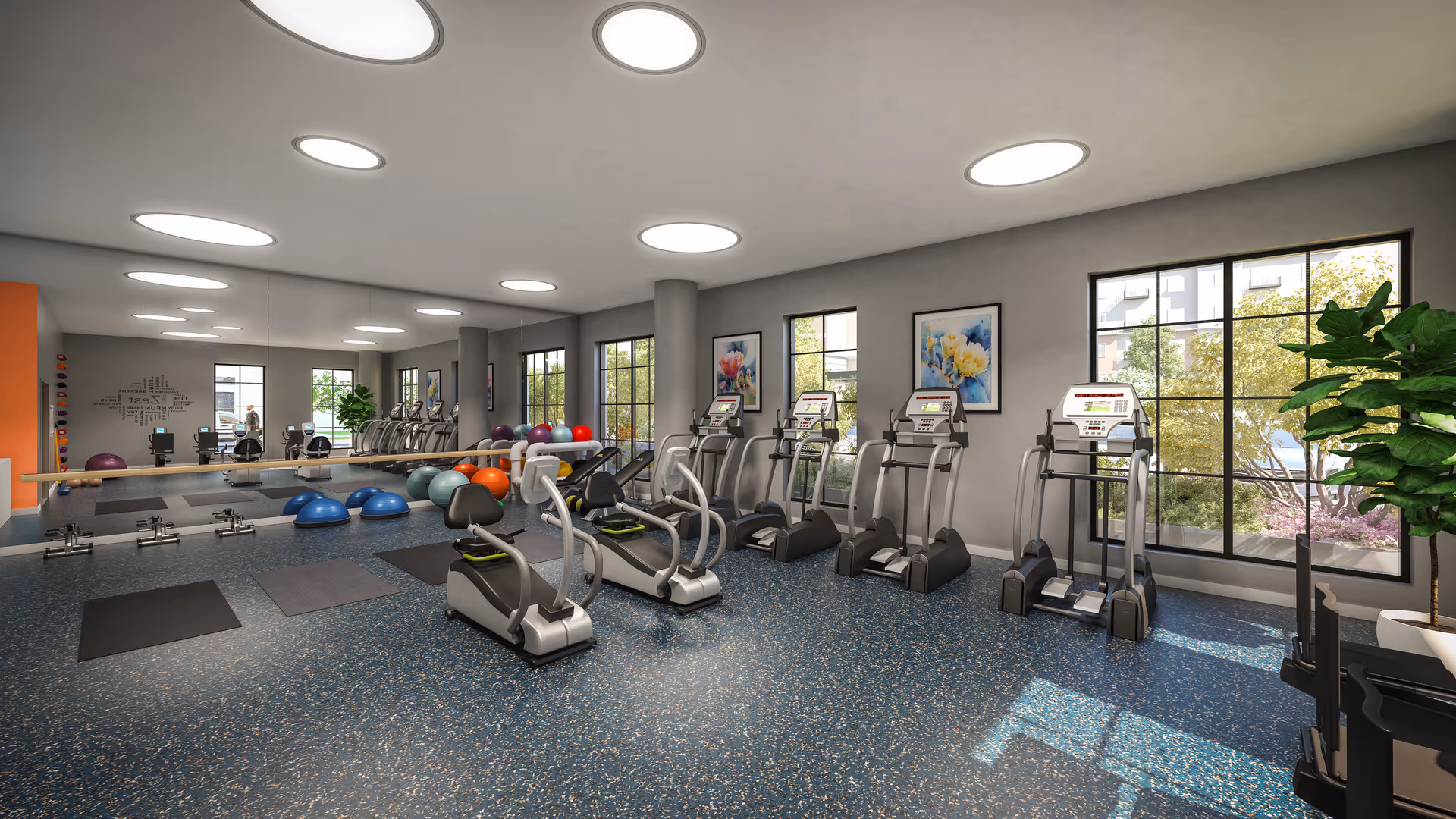 Well-lit fitness center with treadmills, ellipticals, exercise balls, and mats beside large windows.
