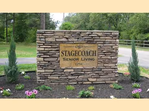 Stone sign for Stagecoach Senior Living sits in a landscaped entry with trees behind.