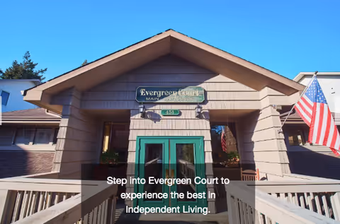 Front entrance of the Evergreen Court building with a ramp leading to green double doors and an American flag.