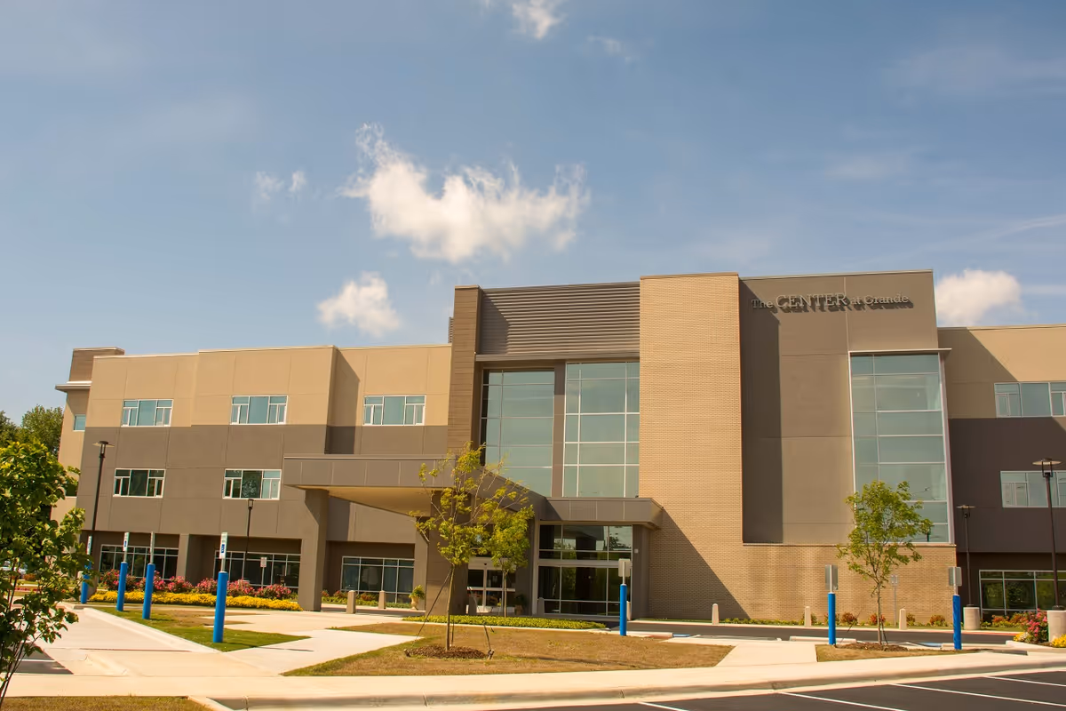 Exterior front view of a modern three-story senior living building with a glass entrance under a blue sky.