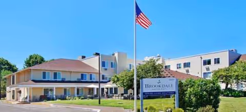 Front exterior view of Brookdale Heritage Plaza with flagpole, sign, and landscaped entrance.