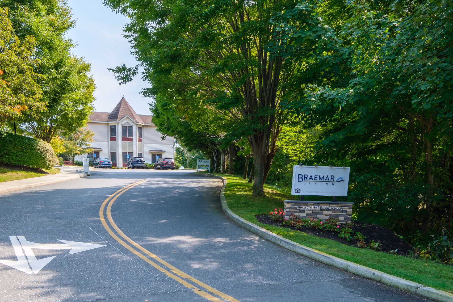 Curved driveway and landscaped entrance sign reading "Braemar" leading to a two-story building surrounded by trees.
