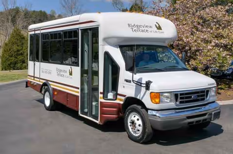 White shuttle bus labeled Ridgeview Terrace of Life Care parked outdoors in a parking lot.