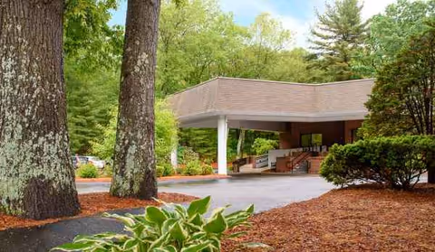 Exterior view of Life Care Center of Acton entrance with trees and covered drop-off.