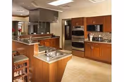 Spacious kitchen with wooden cabinets, stainless steel appliances, and center islands with sinks and seating.
