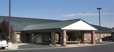 Brick building entrance with a covered drop-off area at a senior living facility.