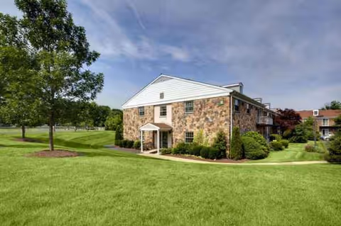 Gwynedd Estates exterior building with stone facade, manicured lawn, and trees.