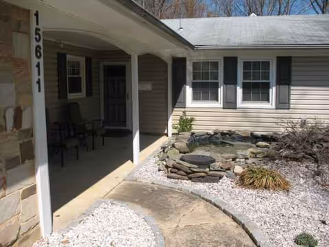 Front exterior of a single-story assisted living building with a covered porch and seating.