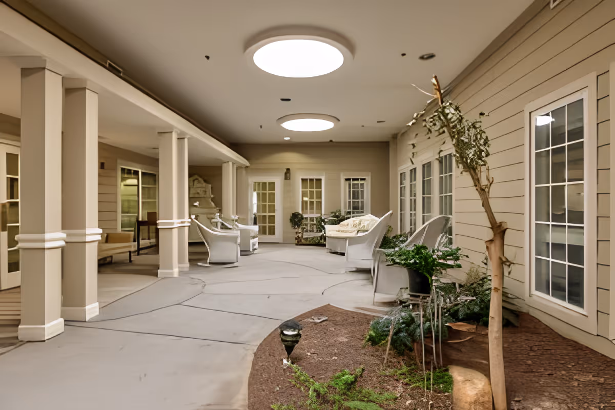 Covered indoor courtyard with wicker seating, potted plants, skylights, and walkways.