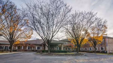 Exterior view of Manorcare Health Services - Montgomeryville showing the entrance, trees, and parking lot.