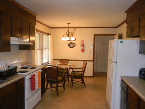 Cozy kitchen and dining area with table, chairs, stove, and refrigerator.