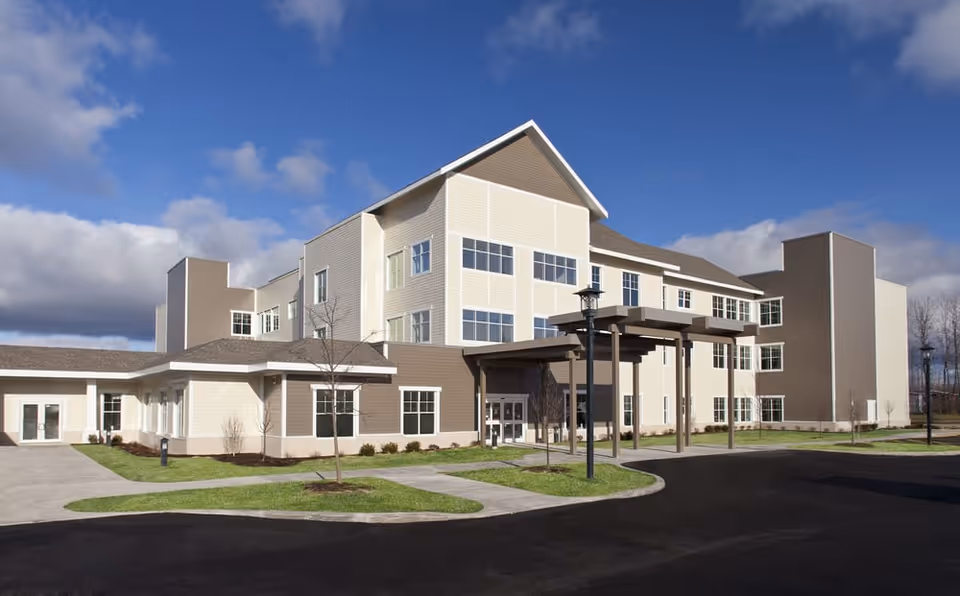 Modern senior living facility exterior with a covered entrance and manicured landscaping.