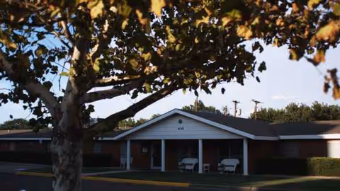 Exterior view of Slaton Care Center front entrance with chairs and a tree