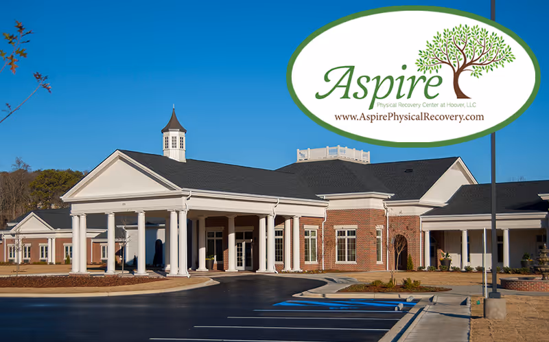 Exterior view of Aspire Physical Recovery Center at Hoover, LLC, a single-story brick building with white columns and a covered entrance, set against a clear blue sky with a parking lot in front.