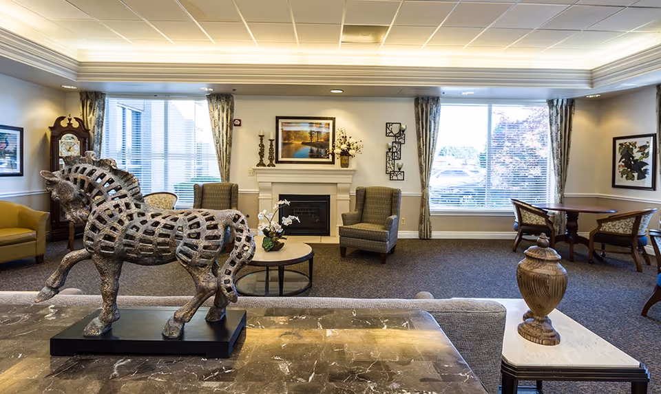Spacious senior living common lounge with a decorative horse sculpture in the foreground, seating areas, a fireplace, and large windows.