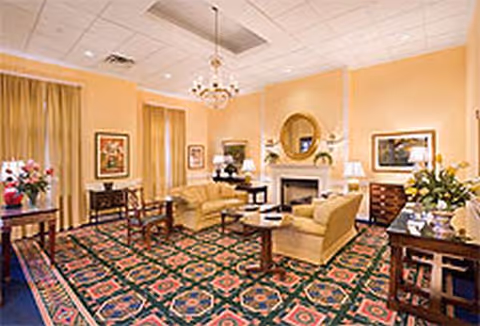 Warm living room with sofas, chairs, fireplace, and patterned carpet.