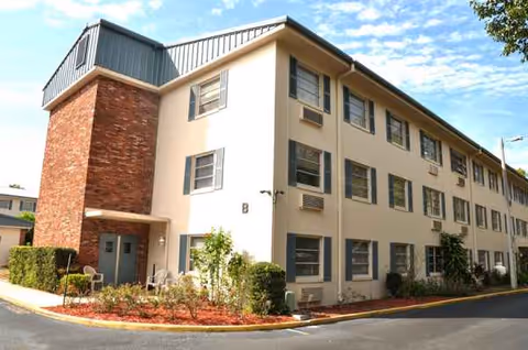 Front view of Florida Gulf Coast Apartments building with windows, brick accent, and landscaping.
