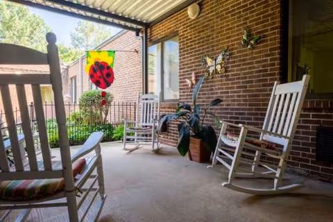 Covered brick porch with white rocking chairs, potted plants, and butterfly decor.