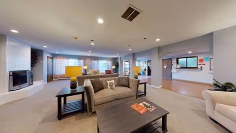 Spacious lounge area with sofas, coffee tables, lamps, and a reception desk visible in the background.