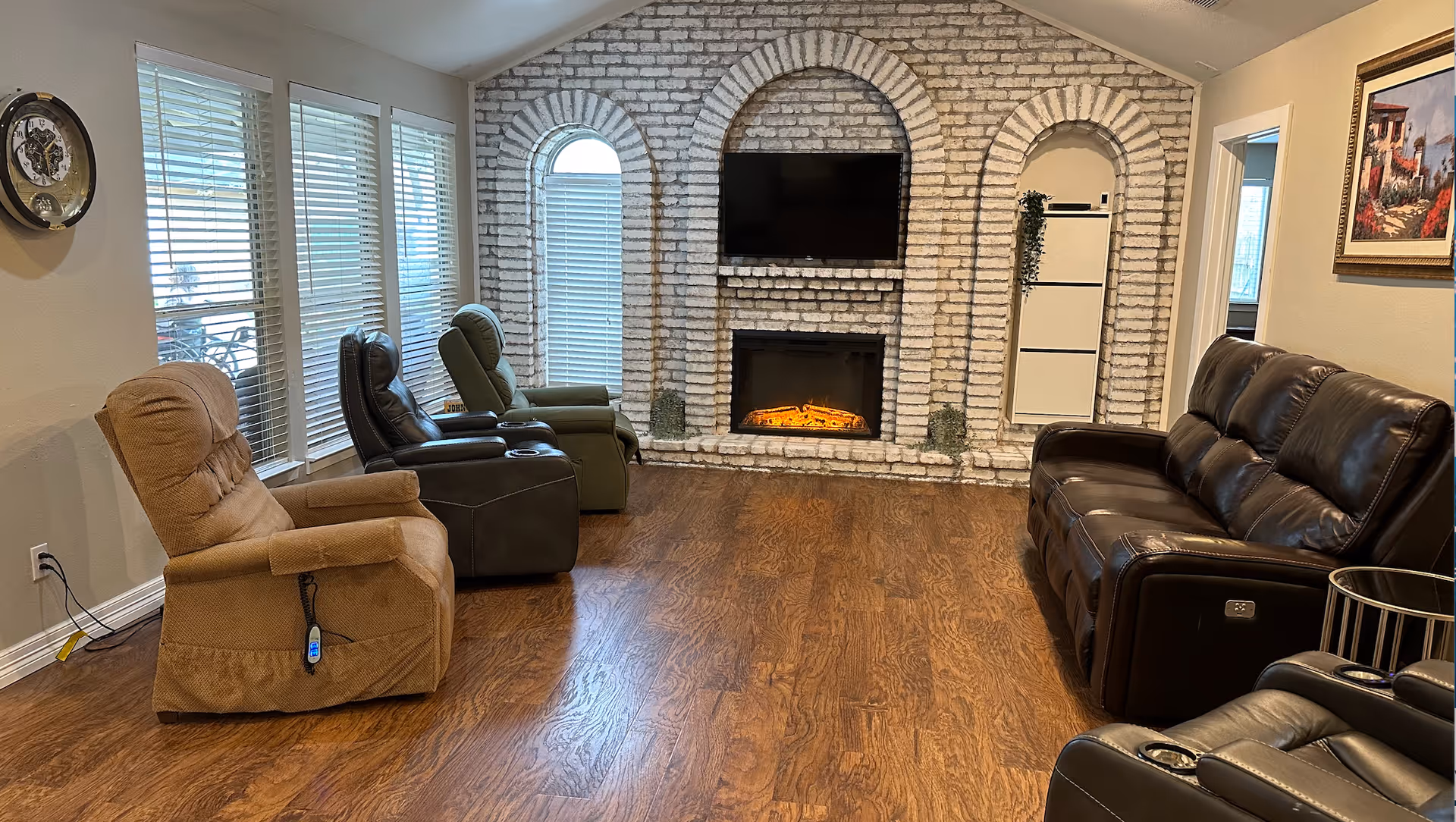 Cozy living room with brick-arched fireplace, TV, recliners, and a leather sofa.