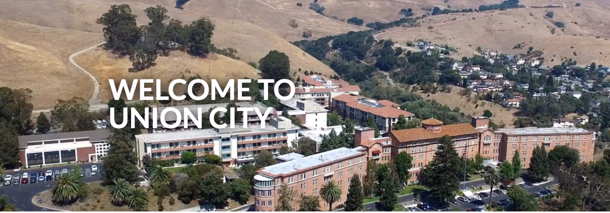 Aerial view of a large senior living facility complex surrounded by trees and hills, with multiple buildings and parking areas visible. Text overlay reads 'WELCOME TO UNION CITY'.