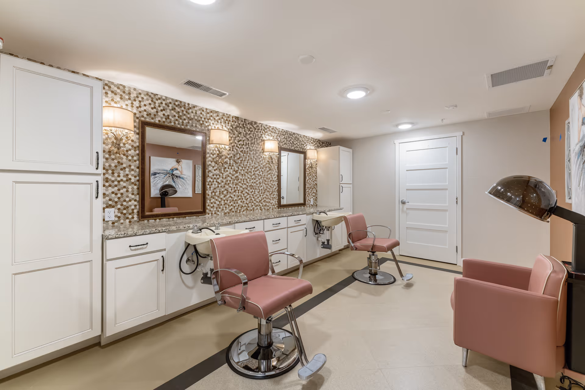 Interior salon with pink styling chairs, shampoo sinks, mirrors, and white cabinetry.