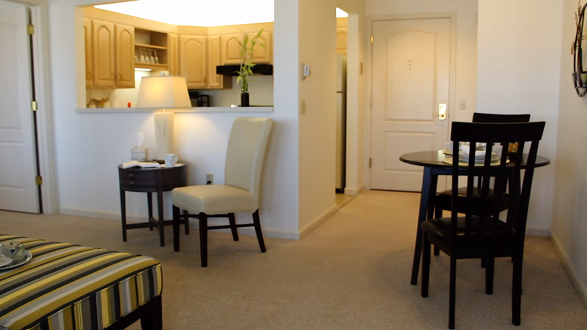 Senior living apartment with kitchenette, dining area, and bed visible in the living space.
