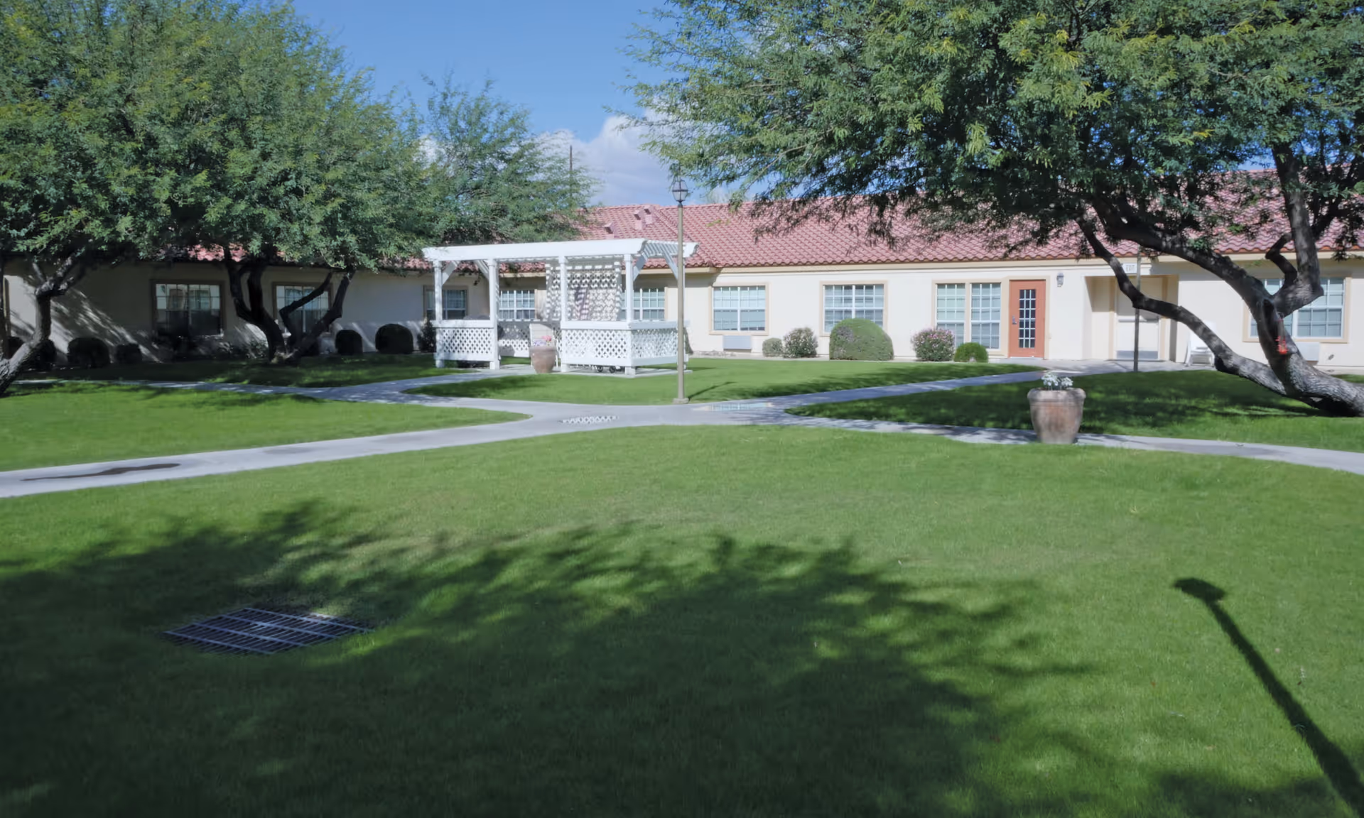 A single-story senior living building with a manicured lawn and a white gazebo.