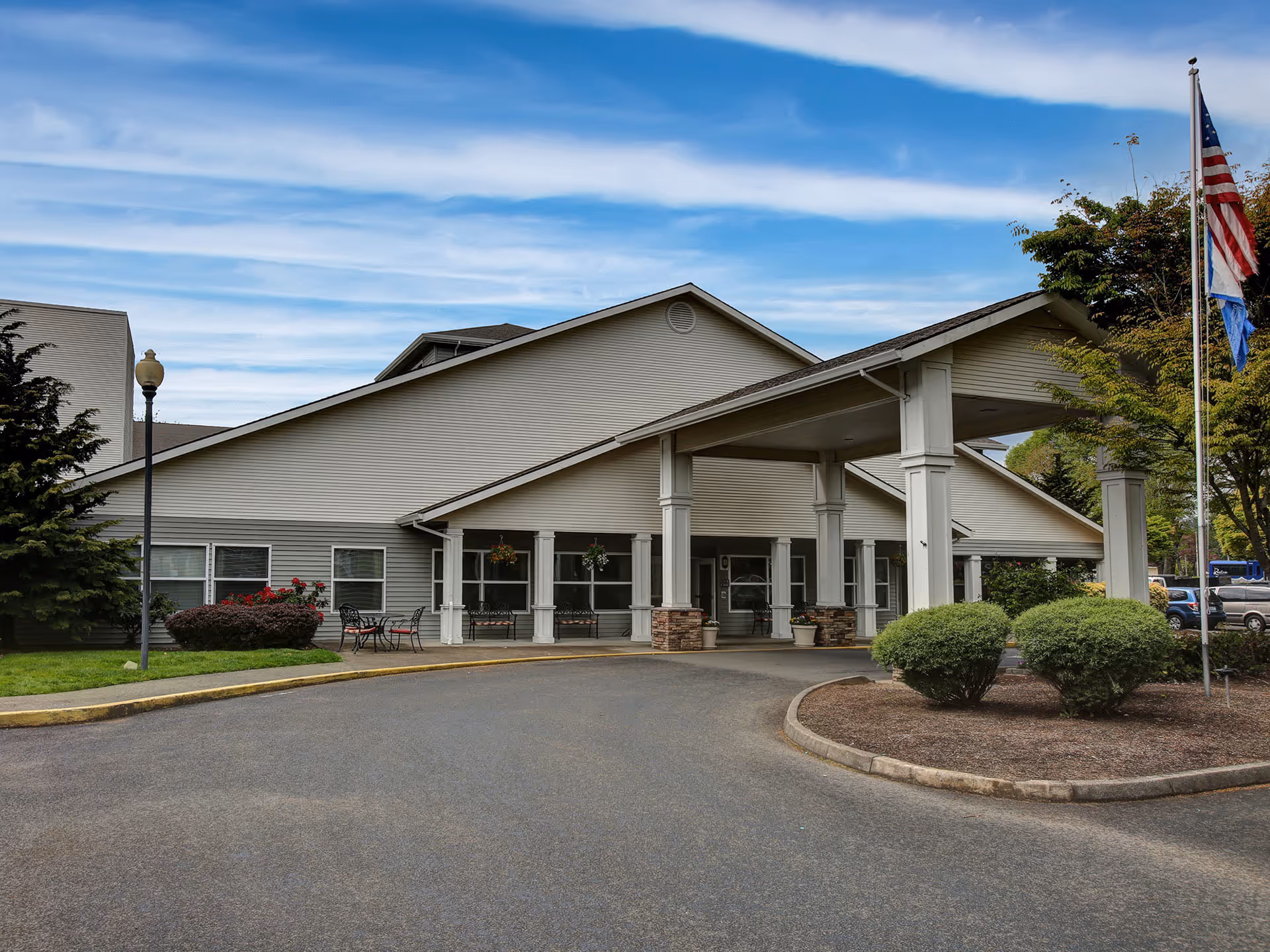 Exterior of a single-story senior living facility with entrance canopy and flagpole.