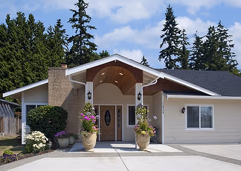 Front entrance of Grace Gentle Care facility with covered porch, potted plants, and a curved arch.