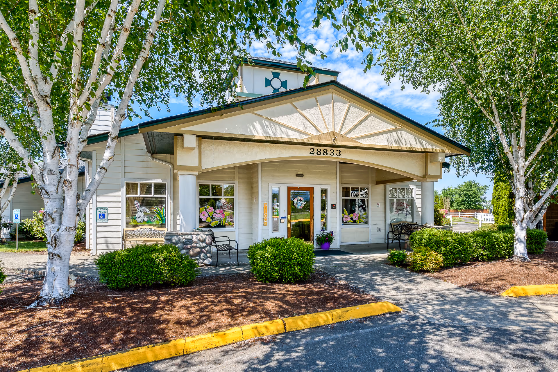 The entrance of Heritage House Buckley Assisted Living & Memory Care surrounded by greenery.