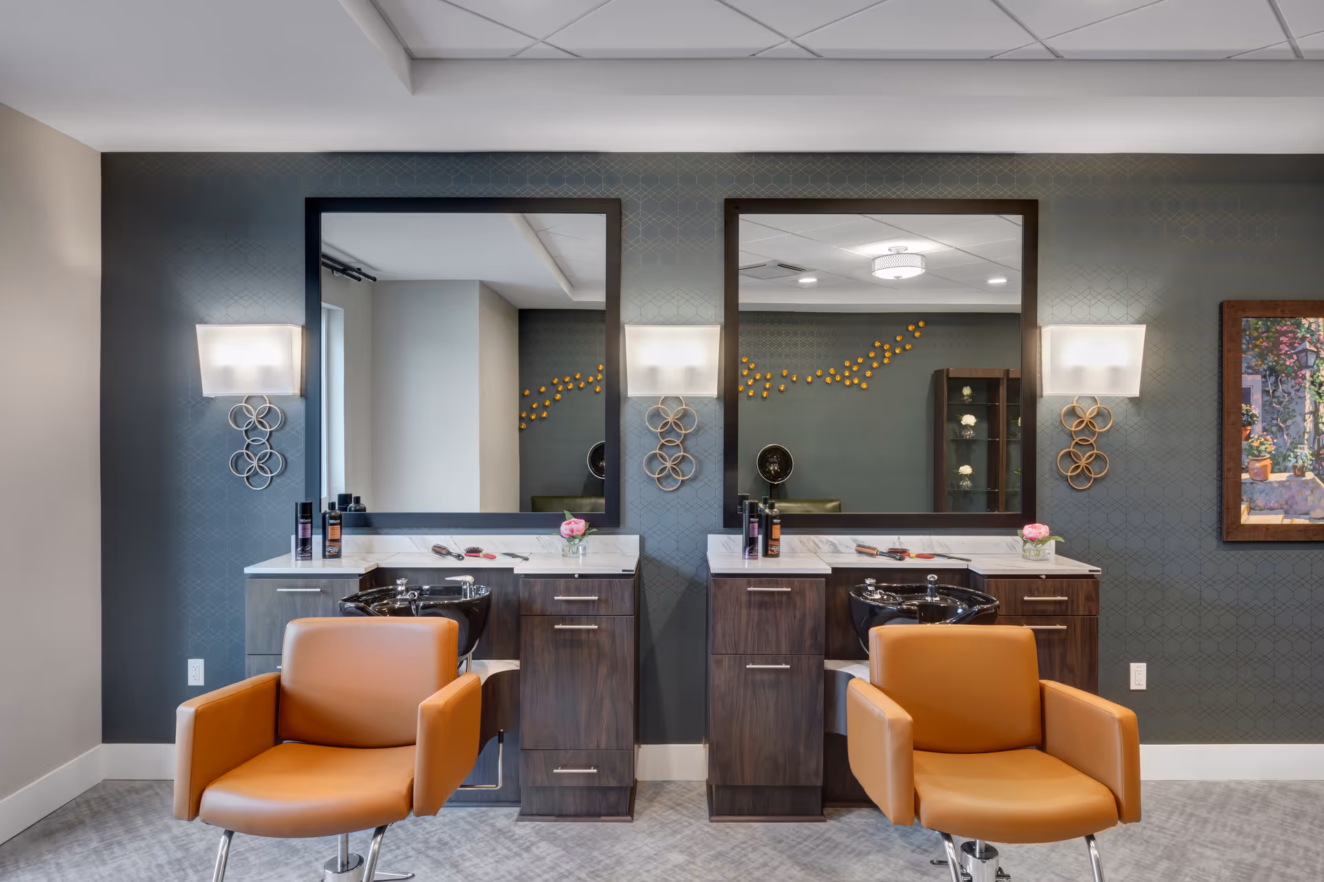 Interior salon area with two styling stations, mirrors, sinks, and orange salon chairs.