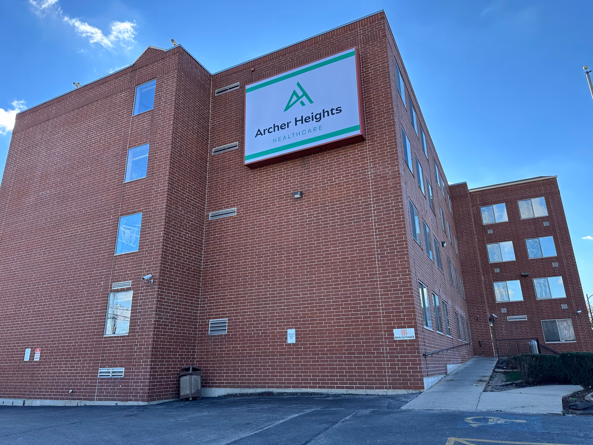 Exterior view of a red-brick multi-story building with an 'Archer Heights Healthcare' sign mounted on the facade.