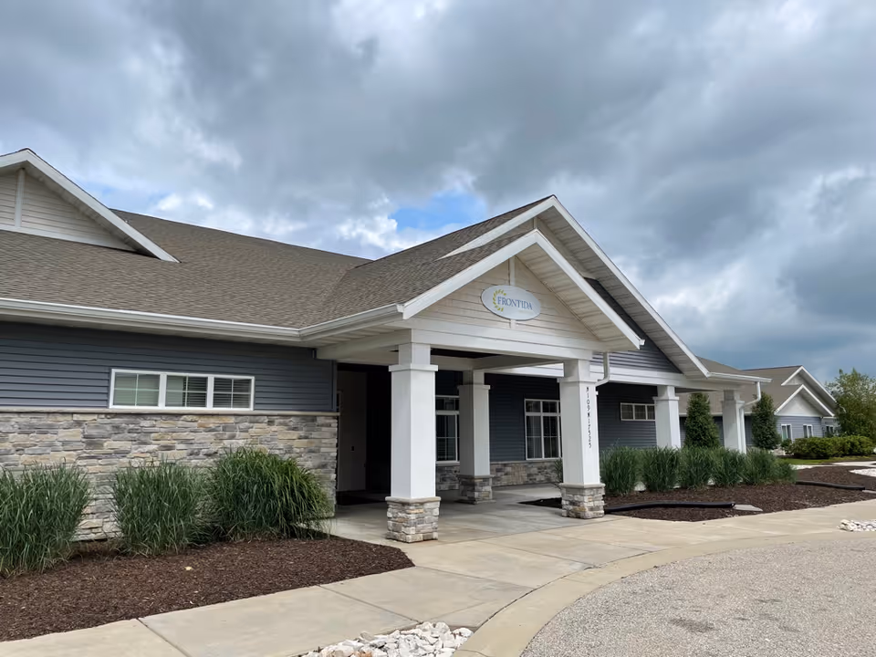 Front view of a modern senior living facility with a covered entrance and stone accents.