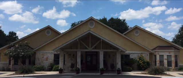 Graceland at Garden Ridge facility front entrance with peaked roof and potted plants.