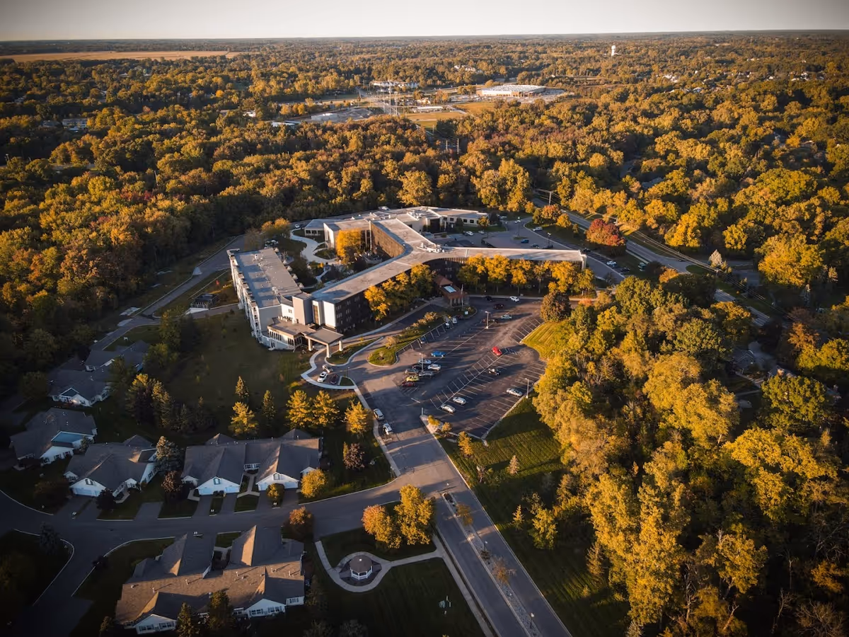 Aerial view of Burcham Hills senior living campus surrounded by autumn-colored trees.