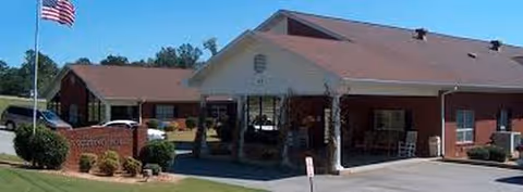 Front view of a brick nursing home with a covered entrance and American flag.