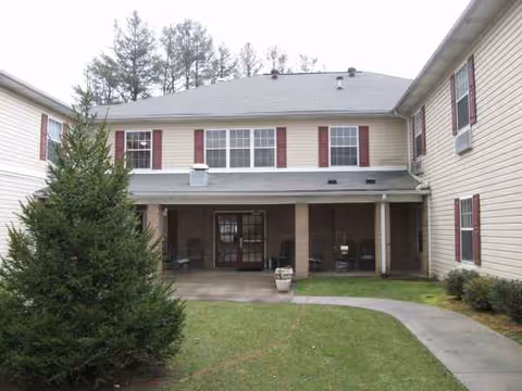 Two-story beige senior living building with a covered front entrance.