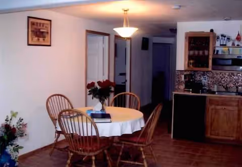 Round table with white tablecloth and chairs in a cozy dining area of a care home.